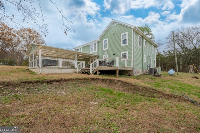 back of property with a wooden deck, a yard, and central AC