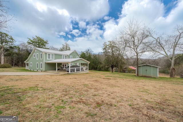 view of front of property with a storage unit, a carport, and a front yard