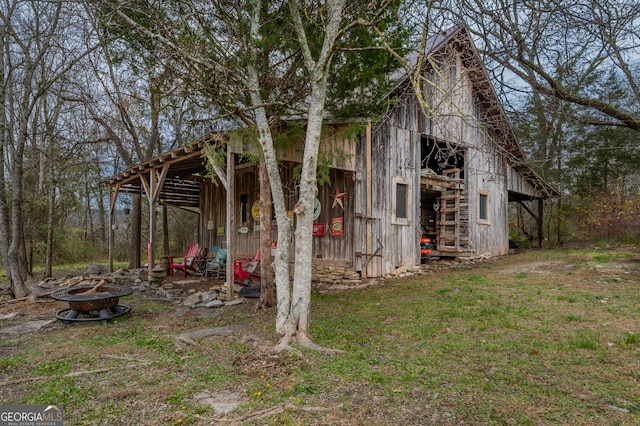 view of side of home featuring an outdoor fire pit and an outdoor structure