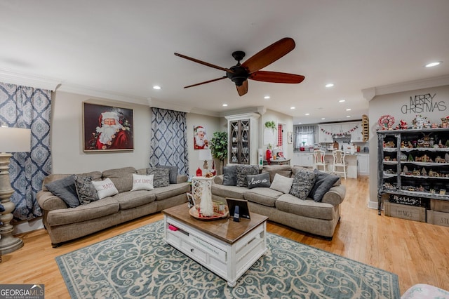 living room with ceiling fan, crown molding, and light hardwood / wood-style flooring