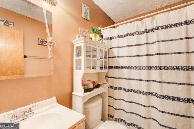 bathroom with a textured ceiling, toilet, walk in shower, and vanity