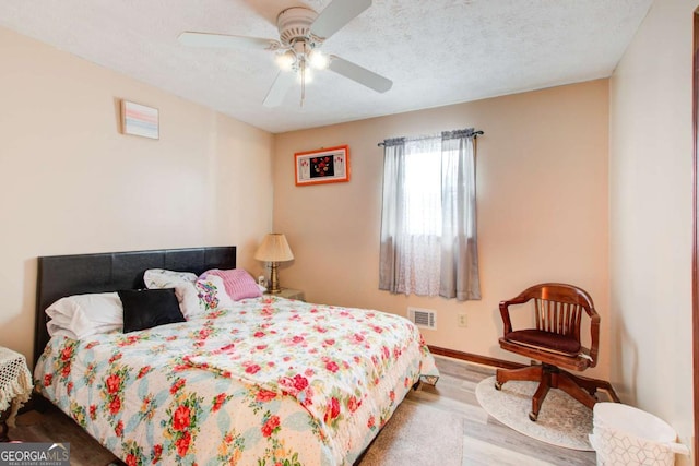 bedroom featuring a textured ceiling, ceiling fan, and wood-type flooring