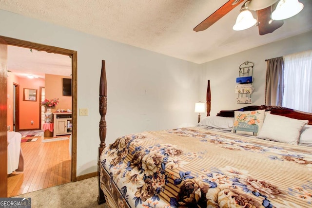 bedroom with ceiling fan, light carpet, and a textured ceiling