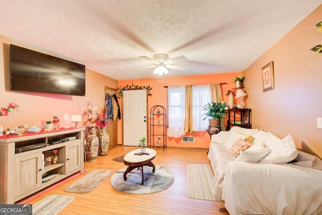 living room featuring a textured ceiling, ceiling fan, and light hardwood / wood-style flooring