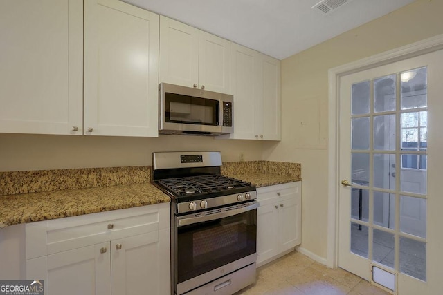 kitchen with light stone counters, appliances with stainless steel finishes, and white cabinets