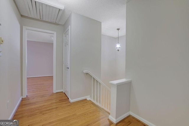 hall featuring a textured ceiling and light hardwood / wood-style flooring