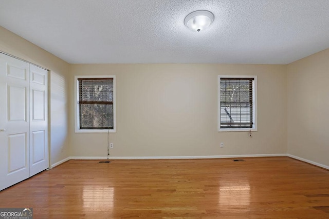 unfurnished bedroom with a closet, a textured ceiling, and light wood-type flooring