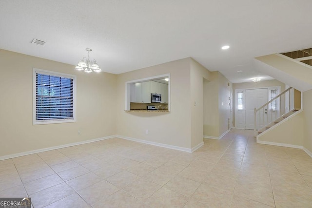 spare room with a notable chandelier and light tile patterned floors