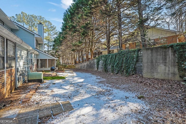 yard covered in snow featuring a sunroom