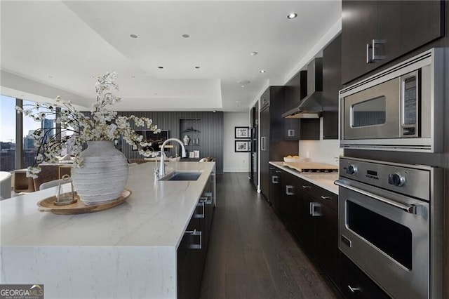 kitchen featuring dark wood-type flooring, sink, appliances with stainless steel finishes, and a center island with sink