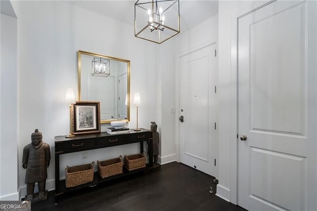 foyer entrance with an inviting chandelier and dark hardwood / wood-style flooring