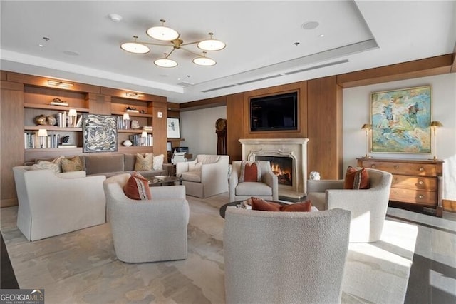 living room with a raised ceiling, built in shelves, and wooden walls