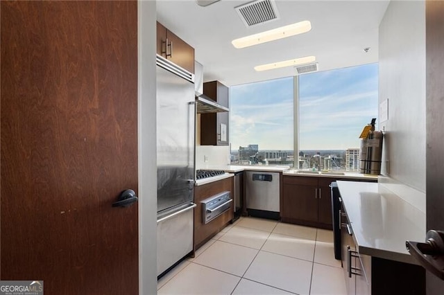 kitchen featuring light tile patterned flooring, appliances with stainless steel finishes, dark brown cabinets, and sink