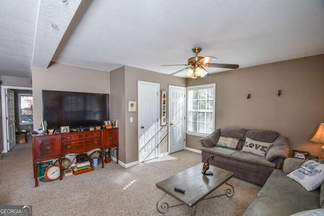 living area with light carpet, a ceiling fan, and baseboards