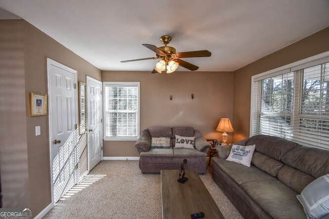 living room with light carpet, baseboards, and a ceiling fan