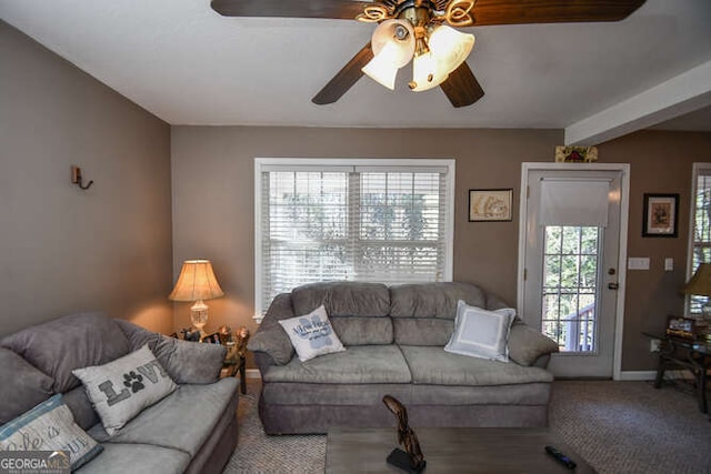 carpeted living area with ceiling fan and baseboards