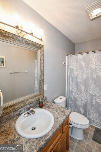 bathroom with toilet, visible vents, tile patterned flooring, and vanity