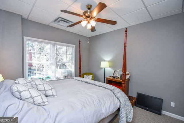 carpeted bedroom featuring a paneled ceiling, baseboards, visible vents, and a ceiling fan