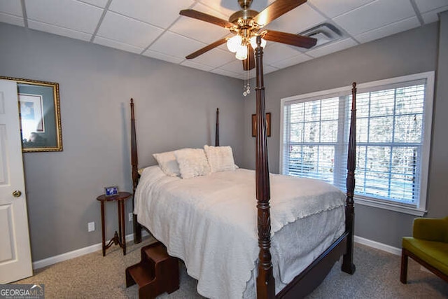 bedroom with a paneled ceiling, multiple windows, visible vents, and baseboards