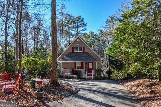 view of front of property with driveway, a porch, and roof with shingles