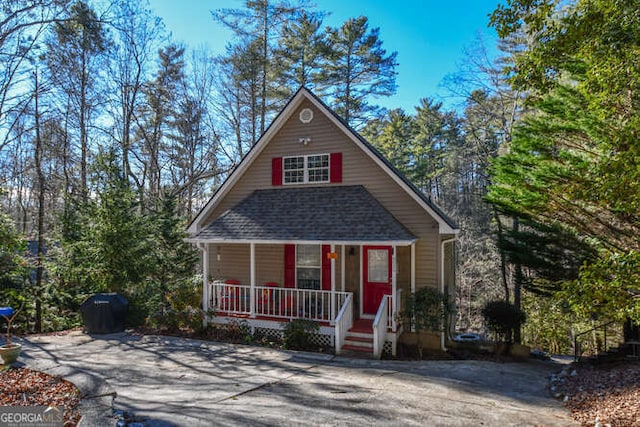 chalet / cabin featuring a shingled roof and a porch