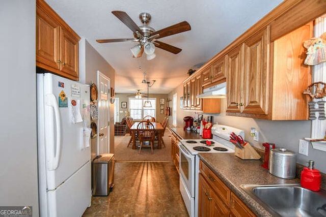 kitchen with brown cabinetry, dark countertops, white appliances, and under cabinet range hood