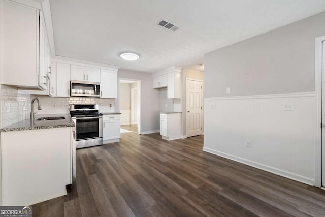 kitchen with white cabinetry, appliances with stainless steel finishes, sink, and dark stone counters