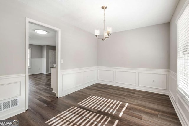 unfurnished room with dark wood-type flooring and an inviting chandelier