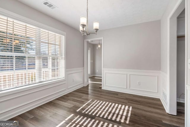 unfurnished dining area with dark wood-type flooring and a chandelier