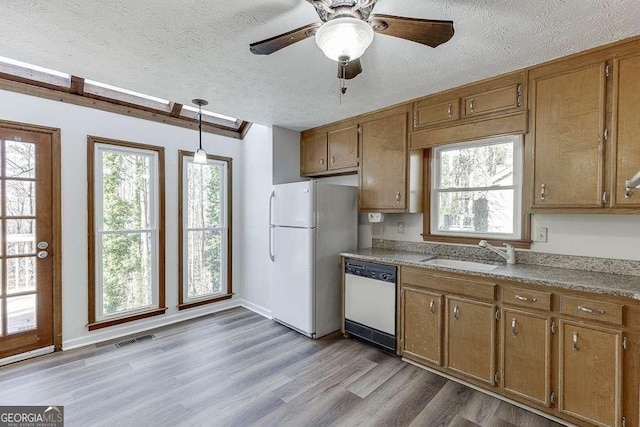 kitchen featuring dishwashing machine, a textured ceiling, white fridge, and hanging light fixtures