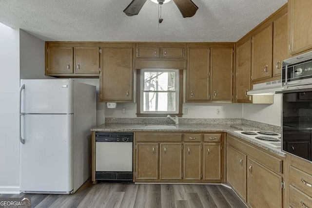 kitchen featuring light hardwood / wood-style floors, sink, white appliances, and a textured ceiling