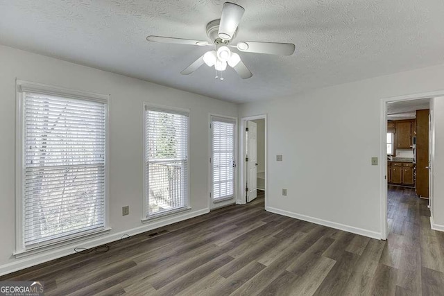 unfurnished room with ceiling fan, dark hardwood / wood-style floors, and a textured ceiling