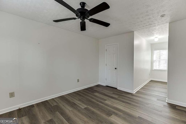 empty room with a textured ceiling, ceiling fan, and dark hardwood / wood-style flooring