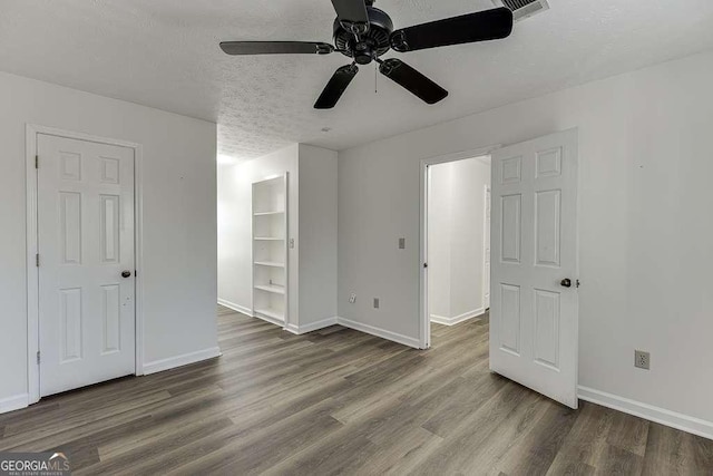 spare room with built in features, a textured ceiling, and hardwood / wood-style floors