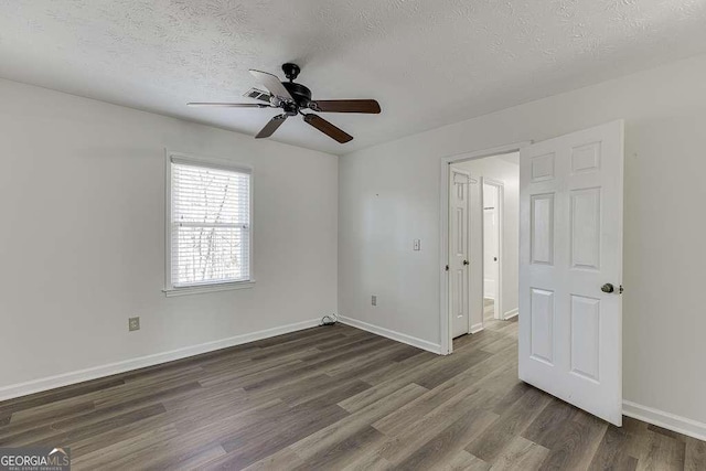 unfurnished room featuring ceiling fan, dark wood-type flooring, and a textured ceiling