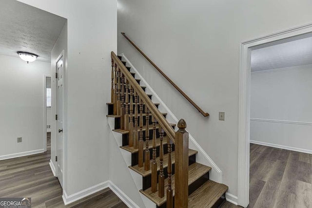 stairway featuring a textured ceiling and hardwood / wood-style flooring