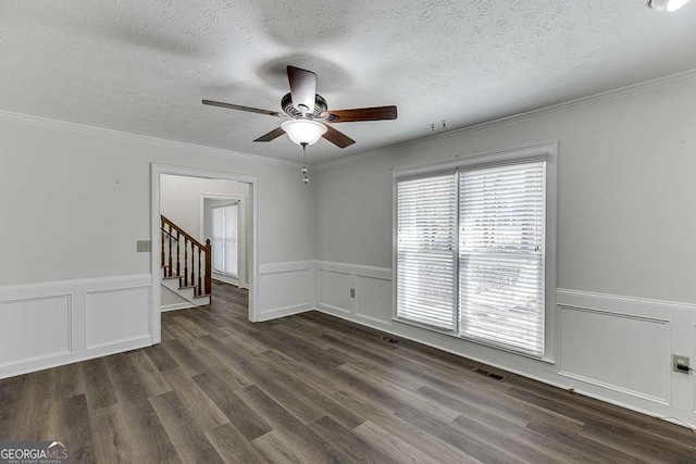 spare room with a textured ceiling, ceiling fan, crown molding, and dark wood-type flooring