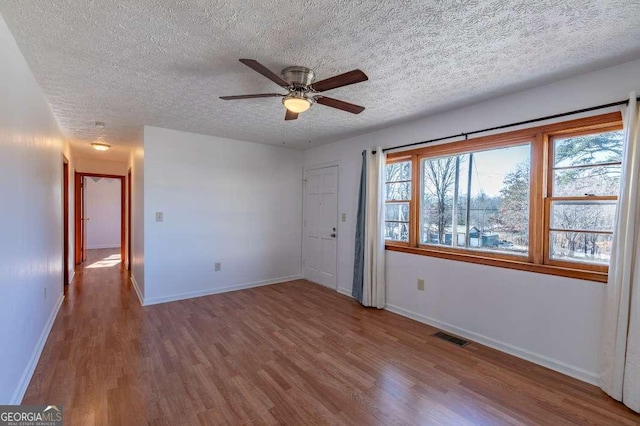 empty room with ceiling fan, hardwood / wood-style floors, and a textured ceiling