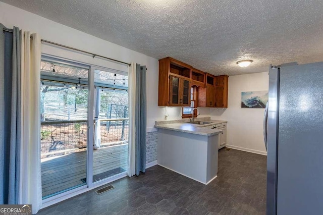 kitchen featuring sink, stainless steel refrigerator, and a textured ceiling