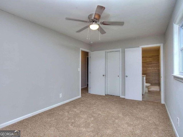 unfurnished bedroom with ensuite bath, light colored carpet, and ceiling fan