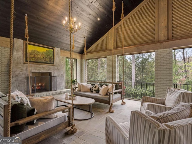 sunroom / solarium with vaulted ceiling, wood ceiling, a fireplace, and an inviting chandelier