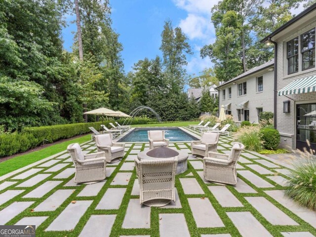 view of swimming pool featuring a patio area, a lawn, and a fire pit