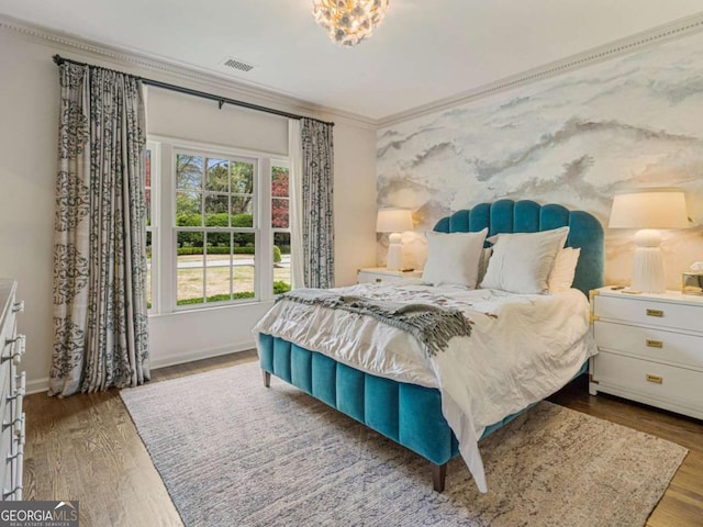 bedroom with baseboards, visible vents, ornamental molding, and wood finished floors