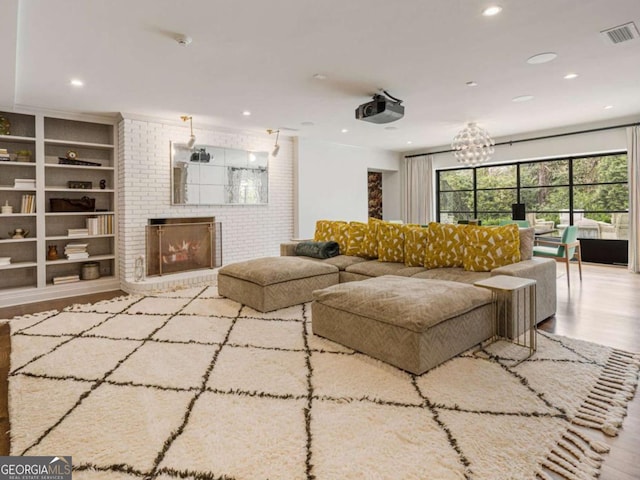 living room with a brick fireplace, wood finished floors, visible vents, and recessed lighting