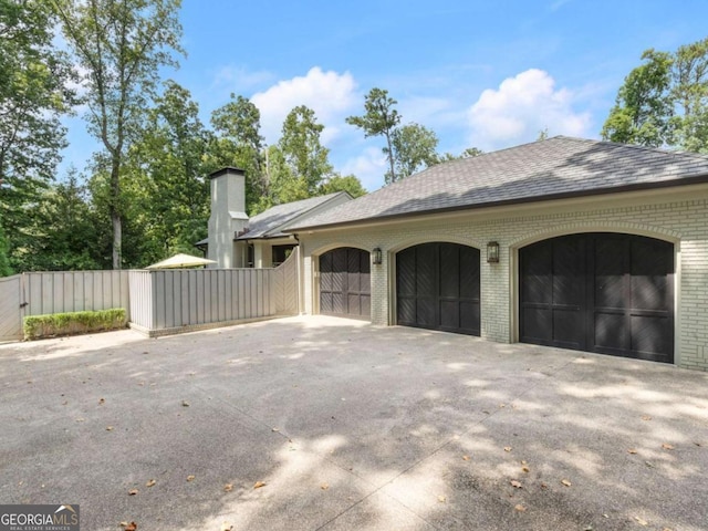 3612 Castlegate Dr NW, Atlanta, GA 30327 - view of property exterior with fence, driveway, brick siding, a garage, and a chimney