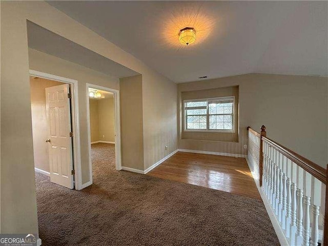 carpeted empty room with vaulted ceiling