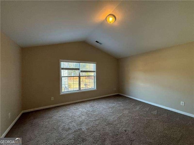 carpeted empty room with lofted ceiling