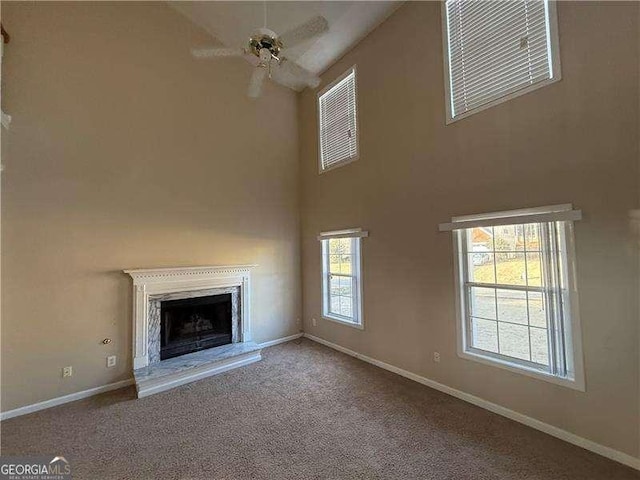 unfurnished living room featuring ceiling fan, a high end fireplace, and carpet flooring