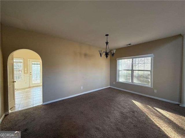 empty room featuring light colored carpet and a chandelier