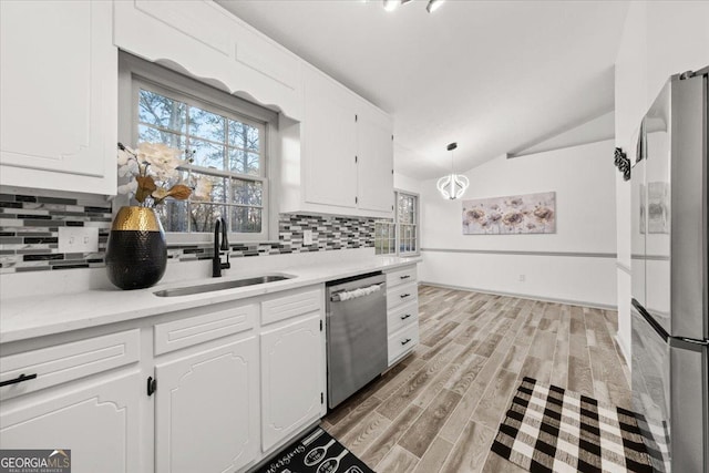 kitchen with vaulted ceiling, stainless steel appliances, white cabinets, and sink